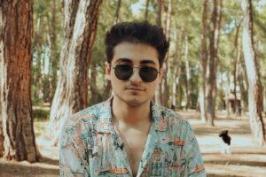 A man wearing sunglasses standing in a forest