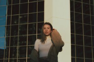 woman in gray cardigan standing beside white concrete building